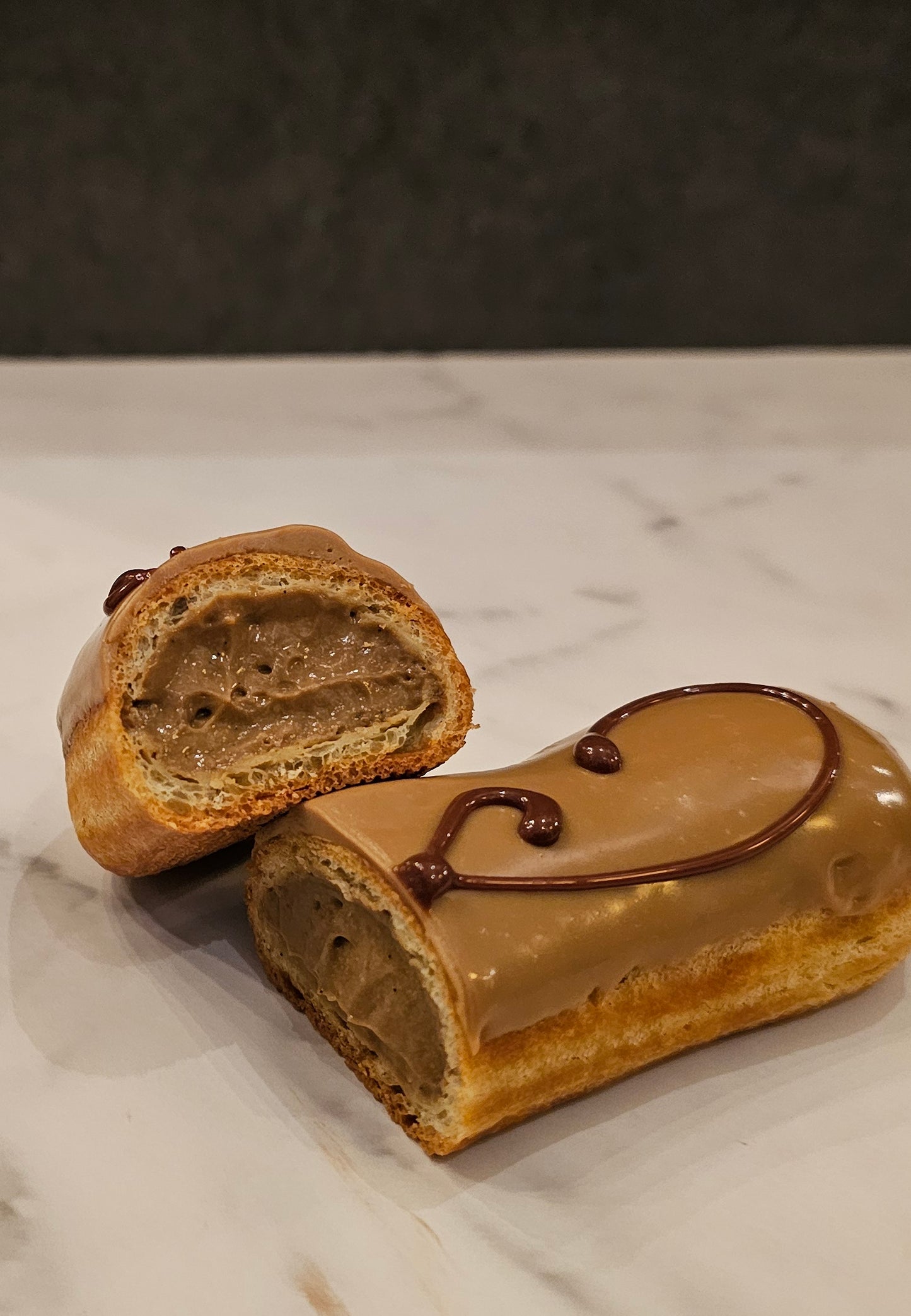 Coffee Éclair, sliced in half, revealing the cream in the middle.