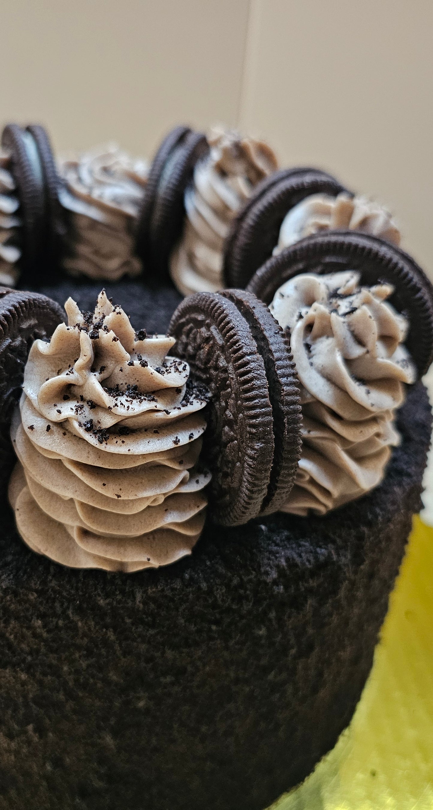 Closeup of an Oreo cake covered in Oreo colored cake crumbs, topped with whole Oreos and spirals of frosting.