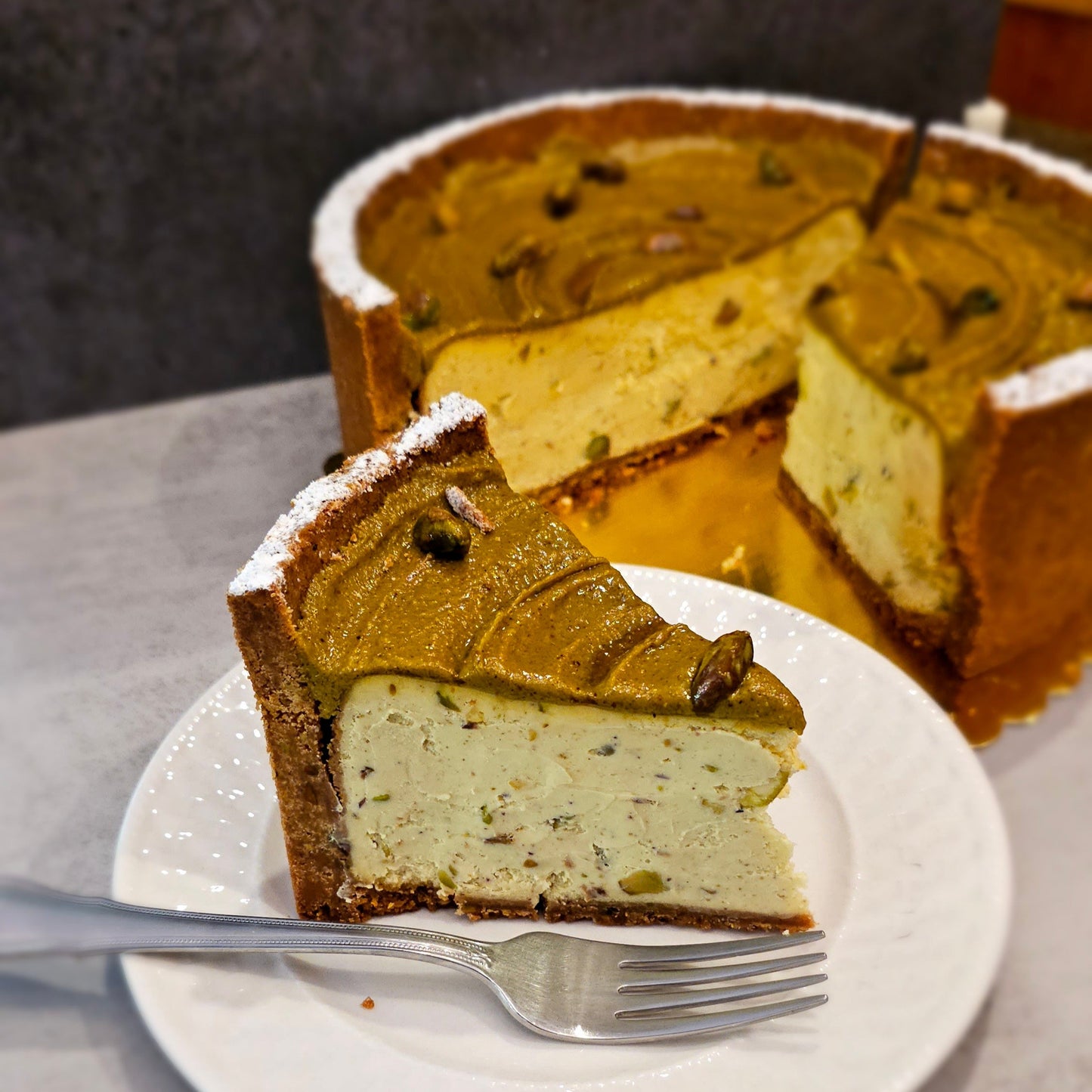 Pistachio Cheesecake, sliced, showing chopped pistachios inside.