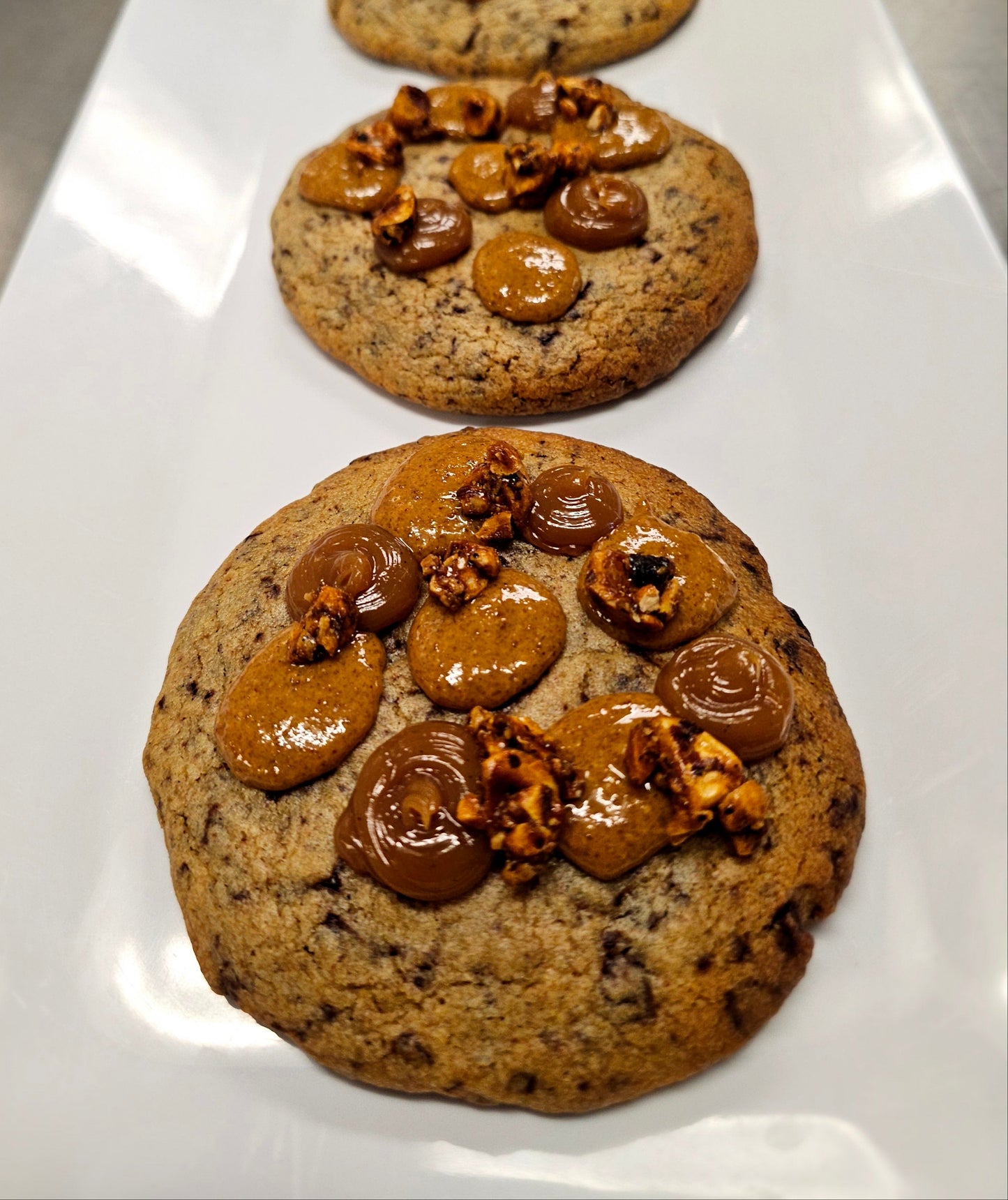 Large chocolate chip cookie with dollops of caramel and praline on top