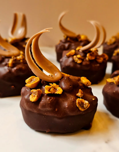 A chocolate tea cake topped with candied hazelnuts and hazelnut crumble, coated in dark and milk chocolate.