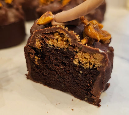 A chocolate tea cake sliced in half and topped with candied hazelnuts and hazelnut crumble, coated in dark and milk chocolate.
