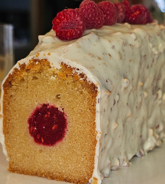 Decorative cake with white frosting and raspberries on top, showing a cross-section revealing raspberry filling.