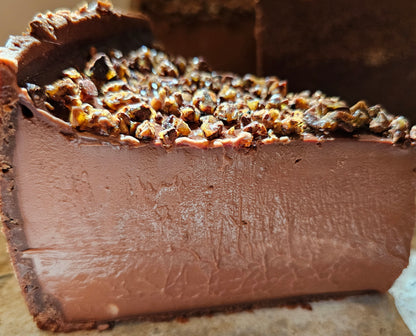 A slice of chocolate flan topped with candied cocoa nibs.