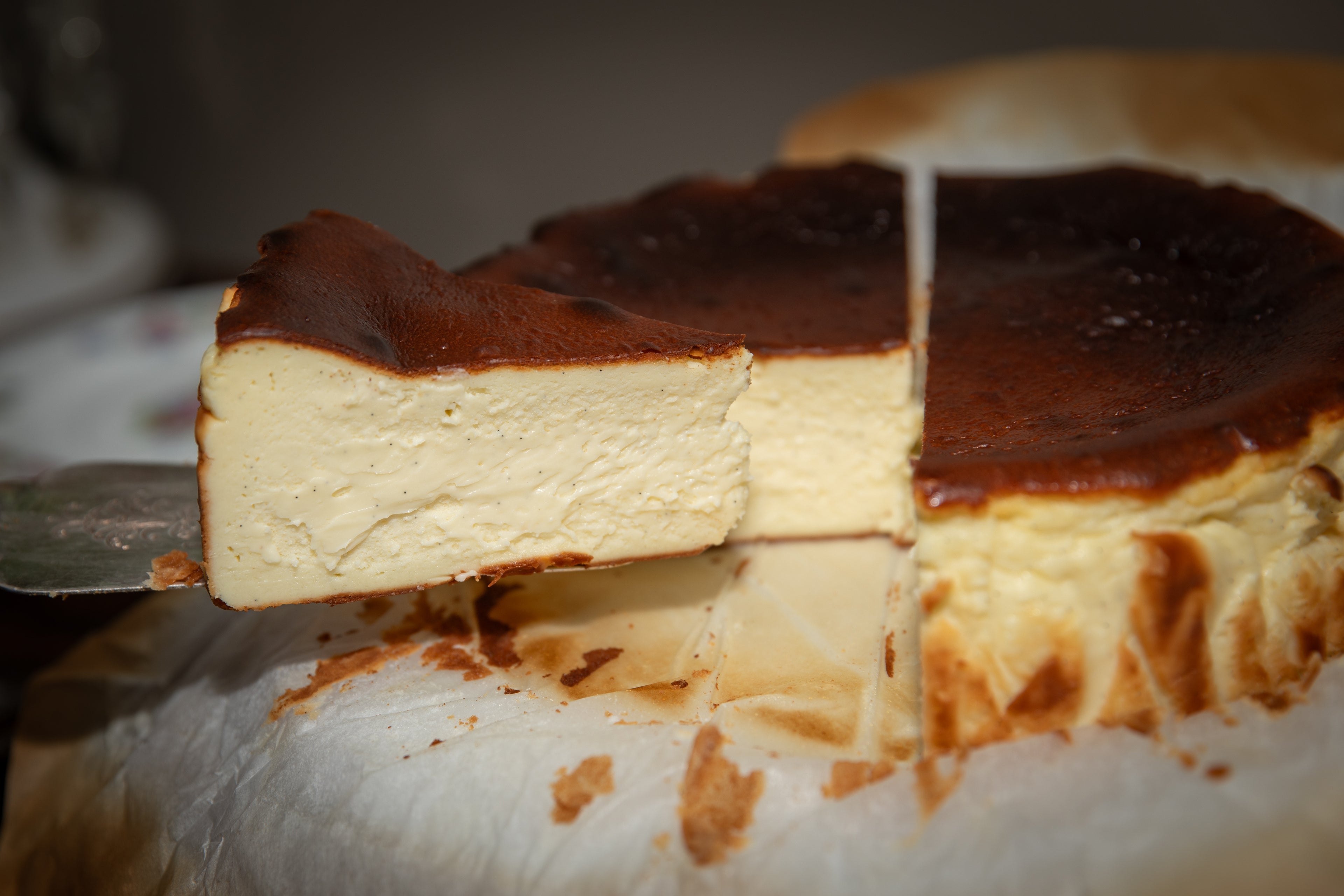 Slice of cheesecake being removed from a whole cheesecake.