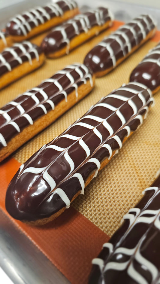 Several eclairs with dark chocolate glaze and white horizontal lines.