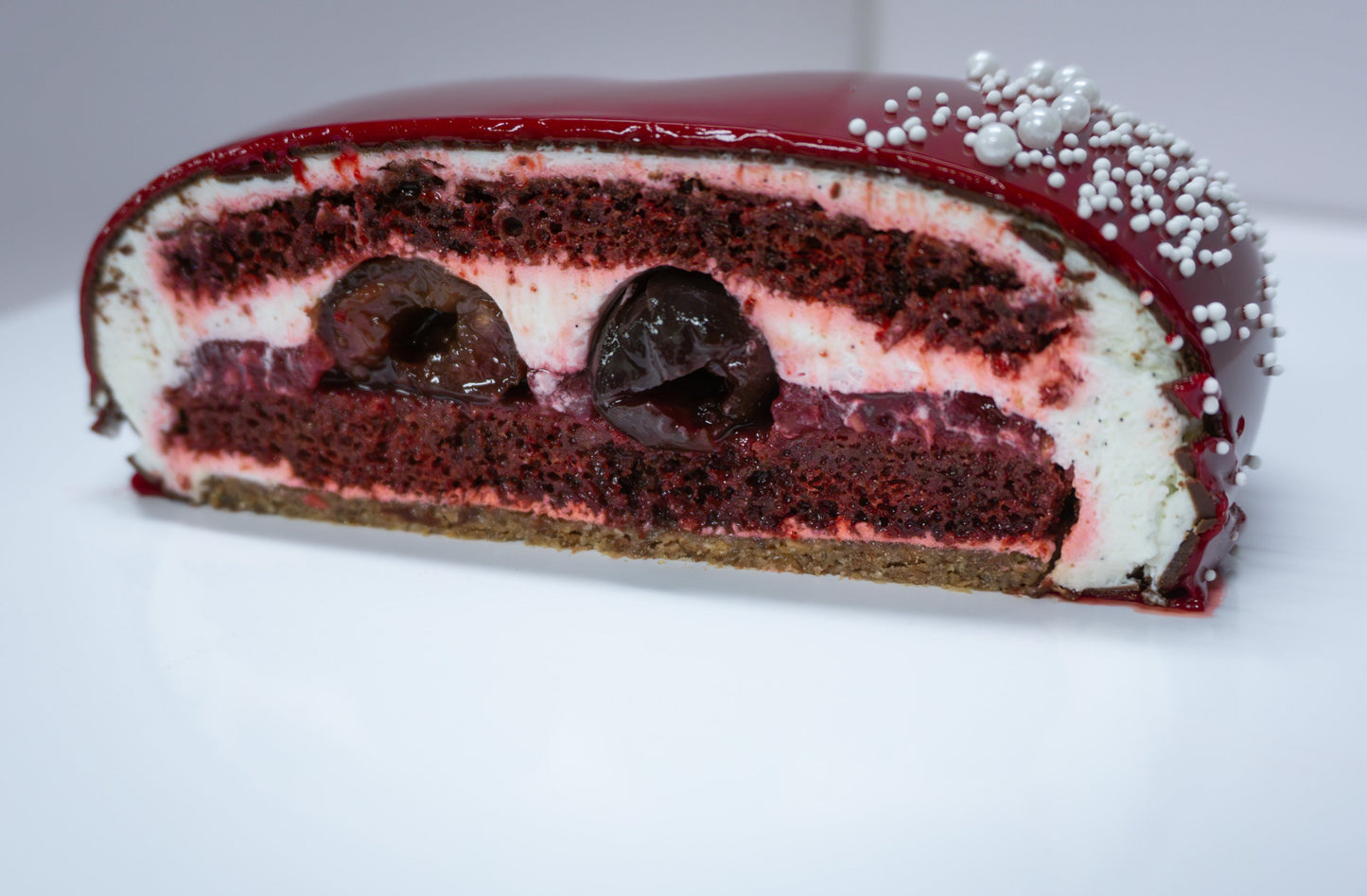 Slice of cake showing layers of cake, cream and whole cherries.
