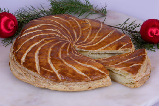 Galette des rois with a slice taken out sitting next to it.