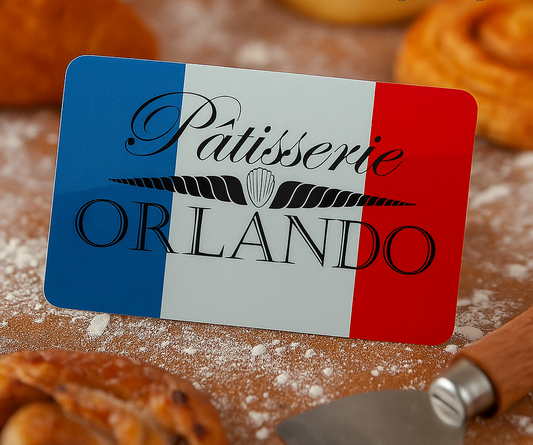 Close up of a gift card sitting on a floury bakers table with the Patisserie Orlando Logo on it