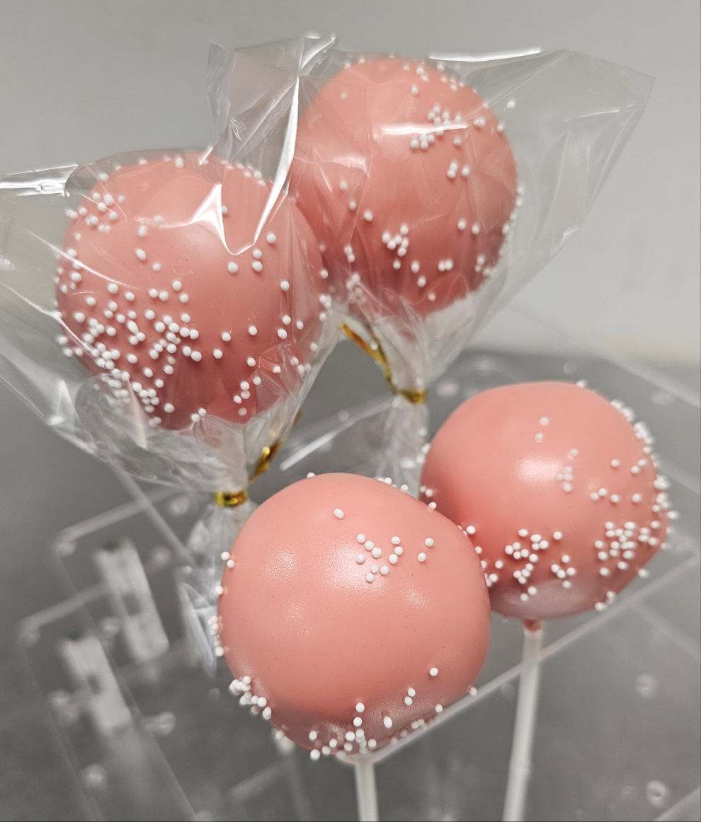 Four pink, round cake pop with white sprinkles