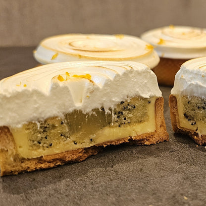 Three Lemon Poppy Seed Tartlets with one sliced in half showing the interior.