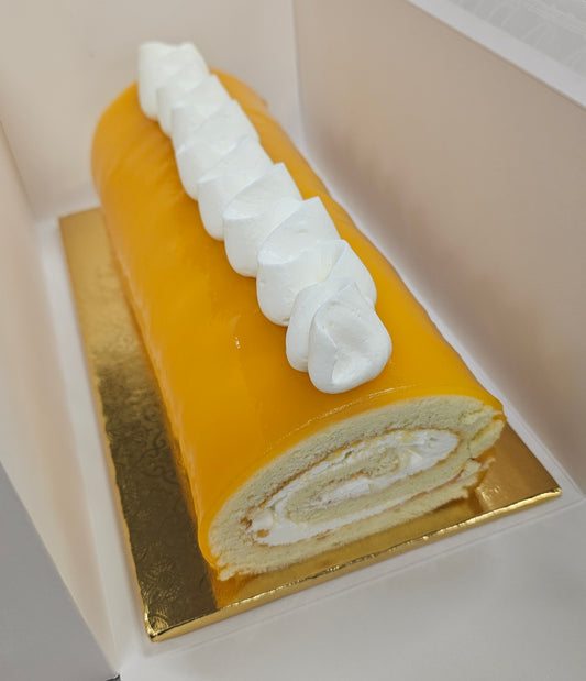 Mango Roll cake with white cream on top, placed on a gold base.