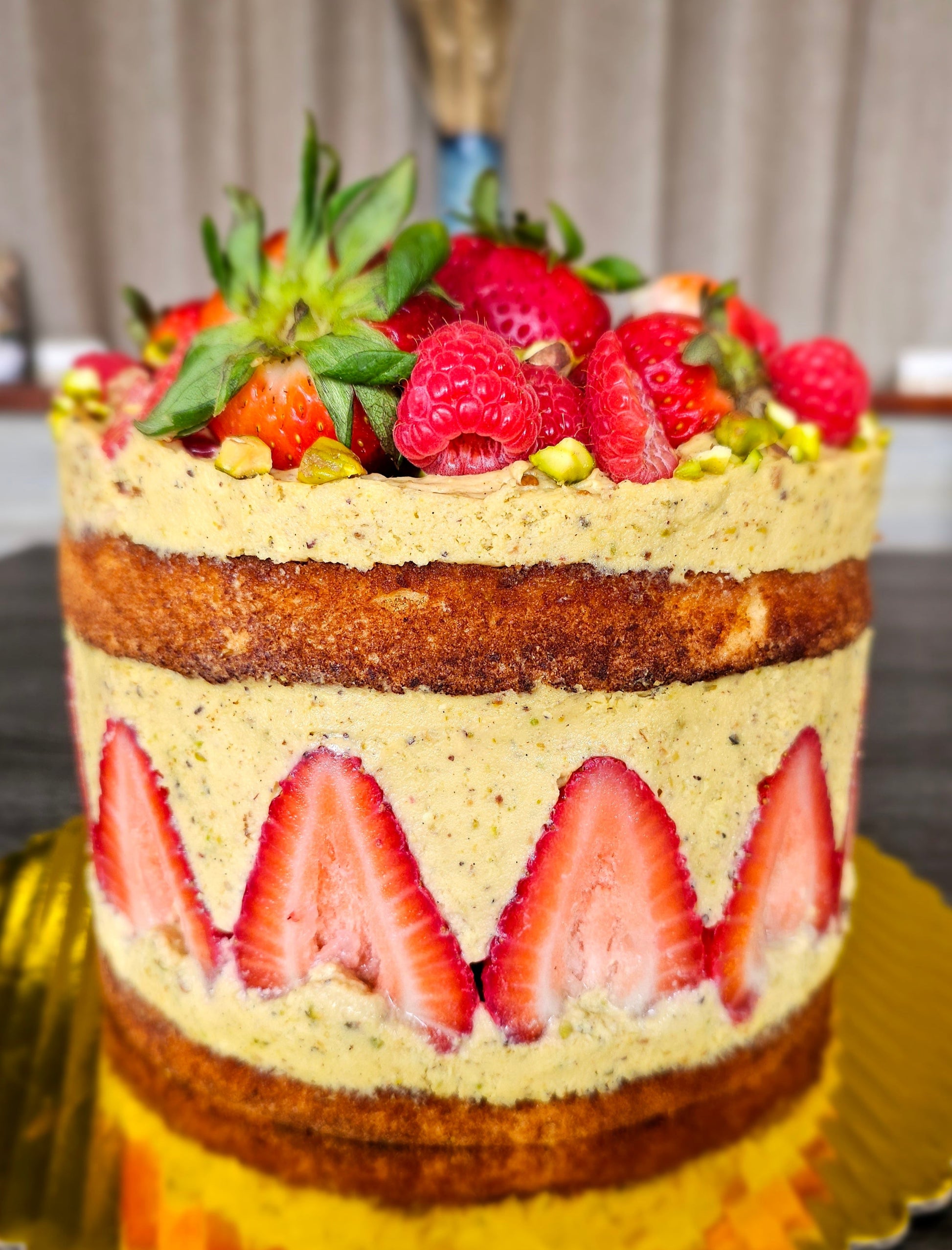 Pistachio Fraisier Cake, With a ring of strawberry embedded in the side. Topped with strawberry and raspberry.