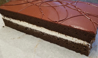 Chocolate cake with a layer of cream on a white surface