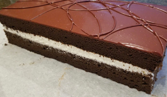 Chocolate cake with a layer of cream on a white surface