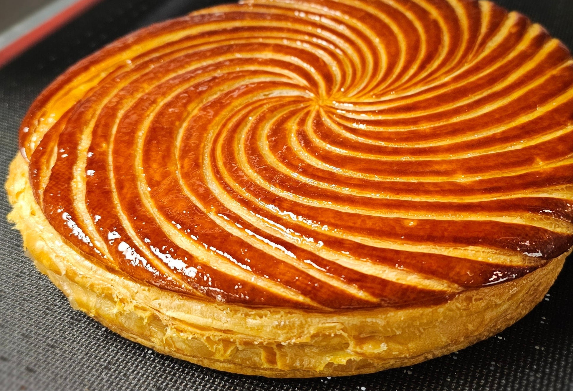 Galette des Rois with a decorative top on a black surface