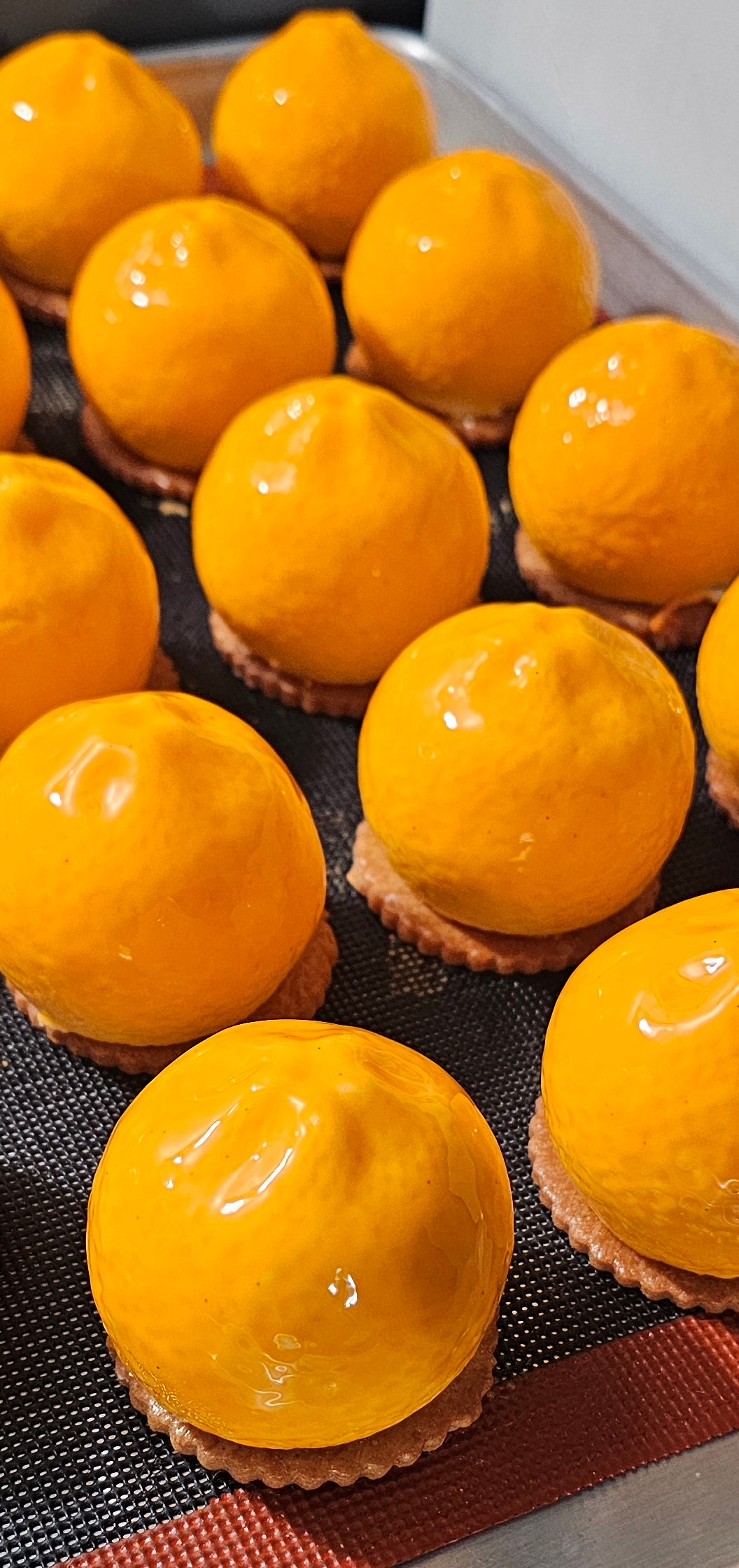 Several Individual mousse cakes shaped like mandarins.