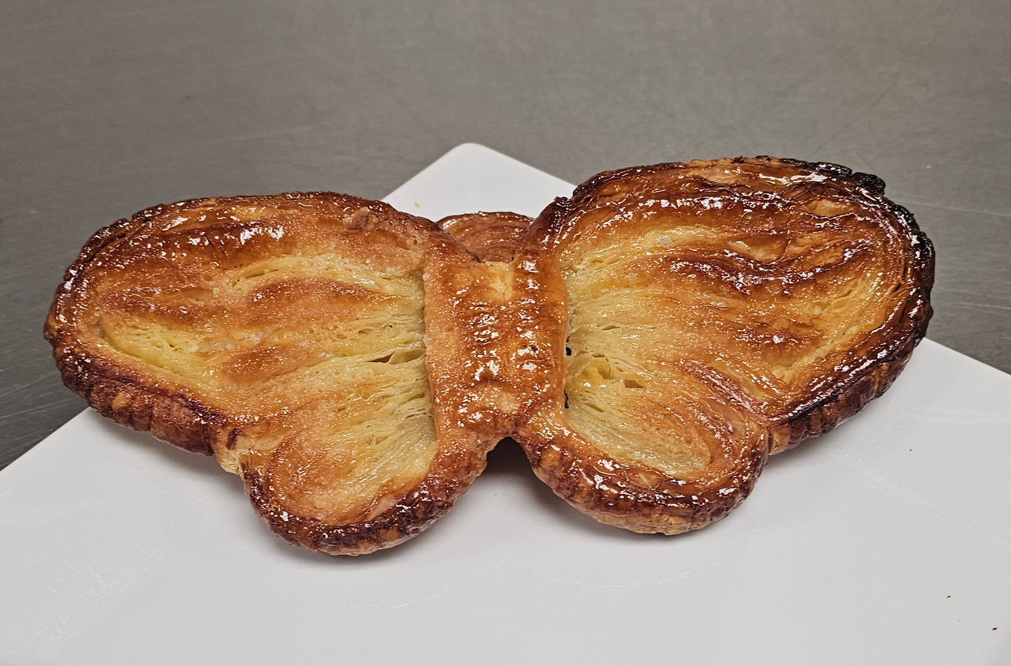 Butterfly-shaped palmier on a white plate with a gray background