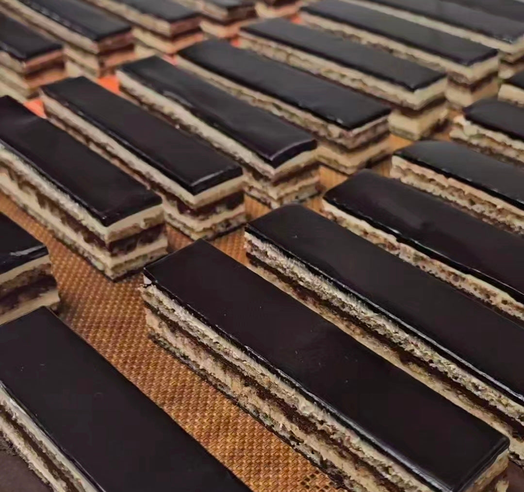 Close-up of a row of rectangular slices of opera cake showing the multiple layers.