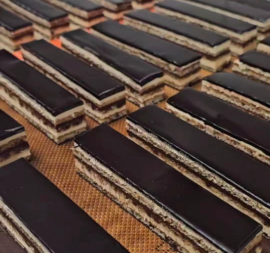 Close-up of a row of rectangular slices of opera cake showing the multiple layers.