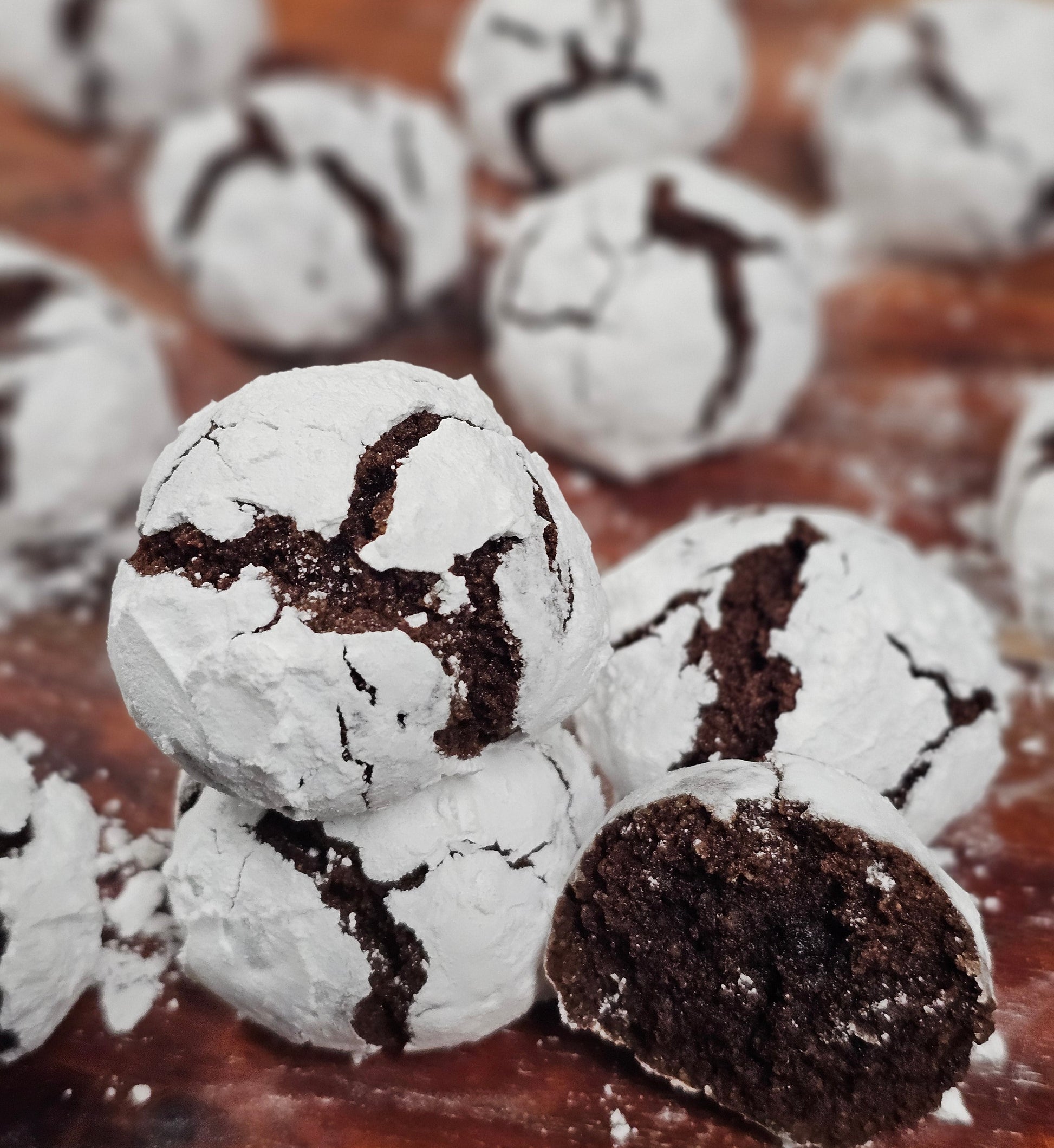 Close-up of crinkle cookies with a chocolate center on a wooden surface.