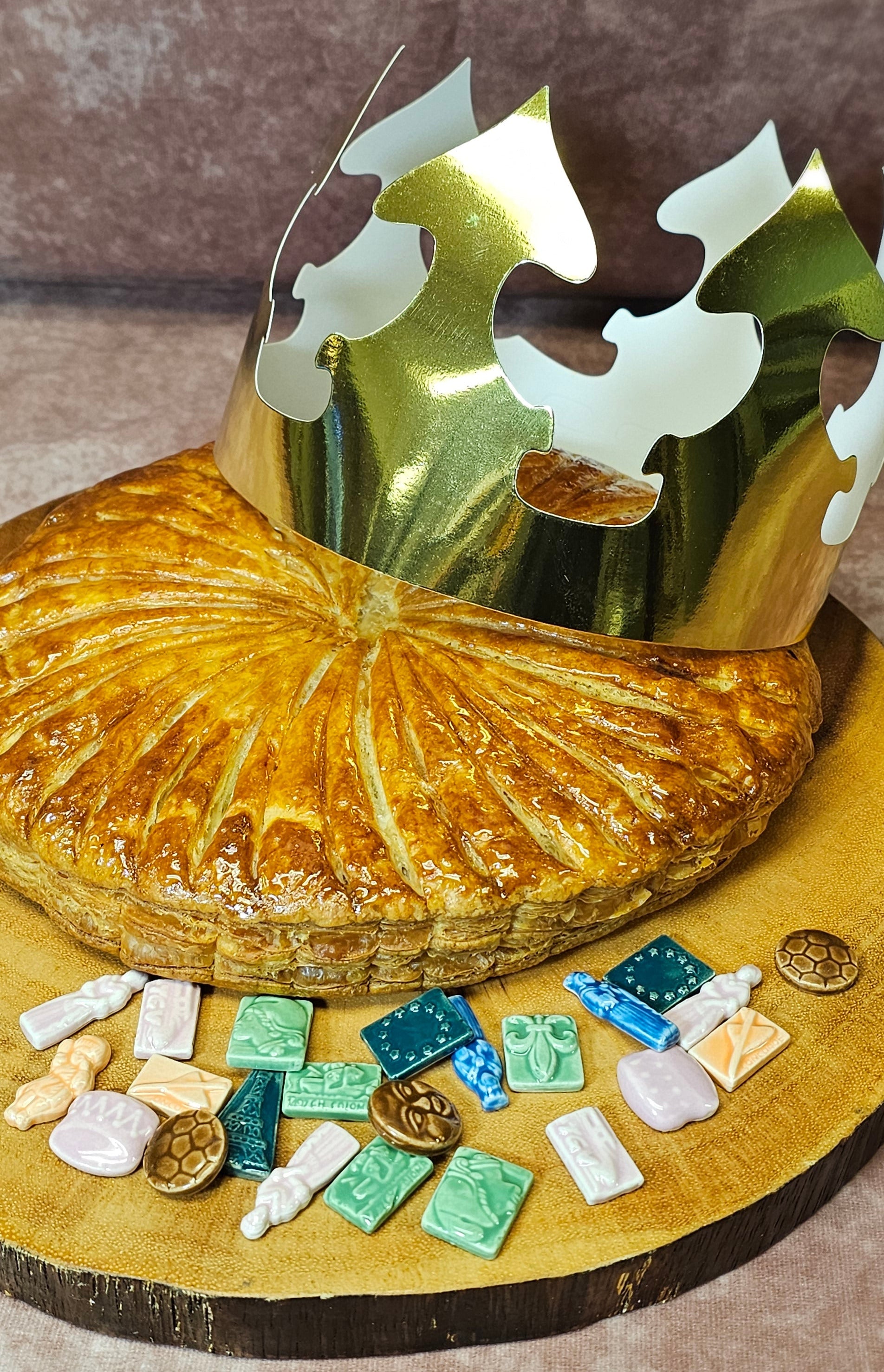 Baked galette des rois  with decorative feves on a wooden board