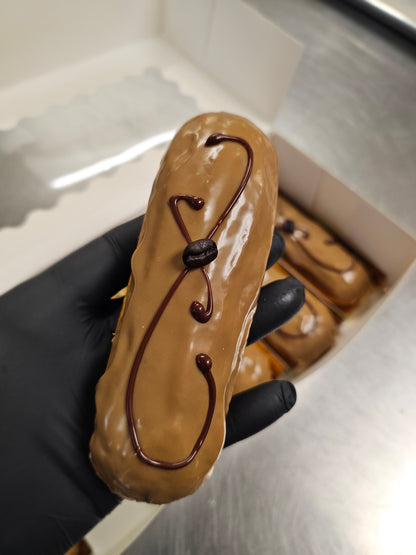 Coffee Éclair held by a gloved hand.