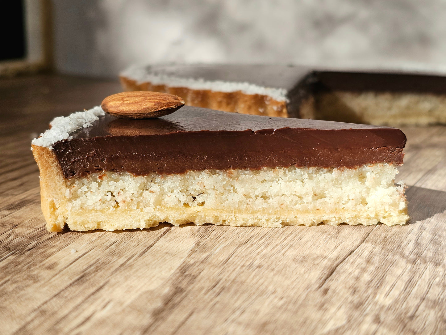 Chocolate coconut tart with a slice on a wooden surface