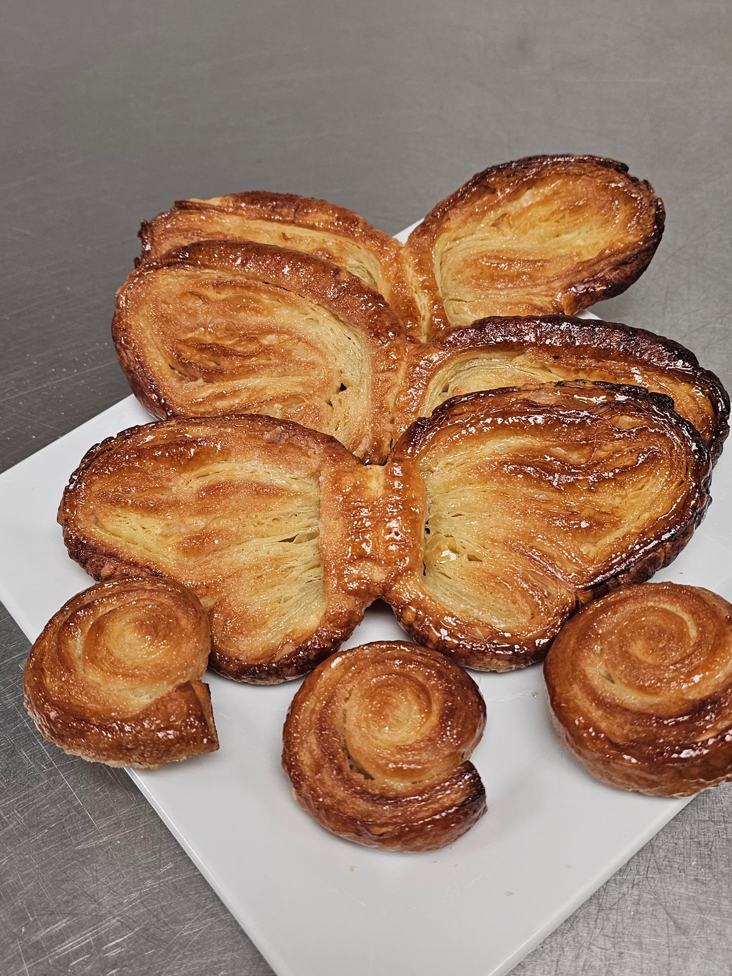 Butterfly-shaped palmiers on a white plate with a gray background