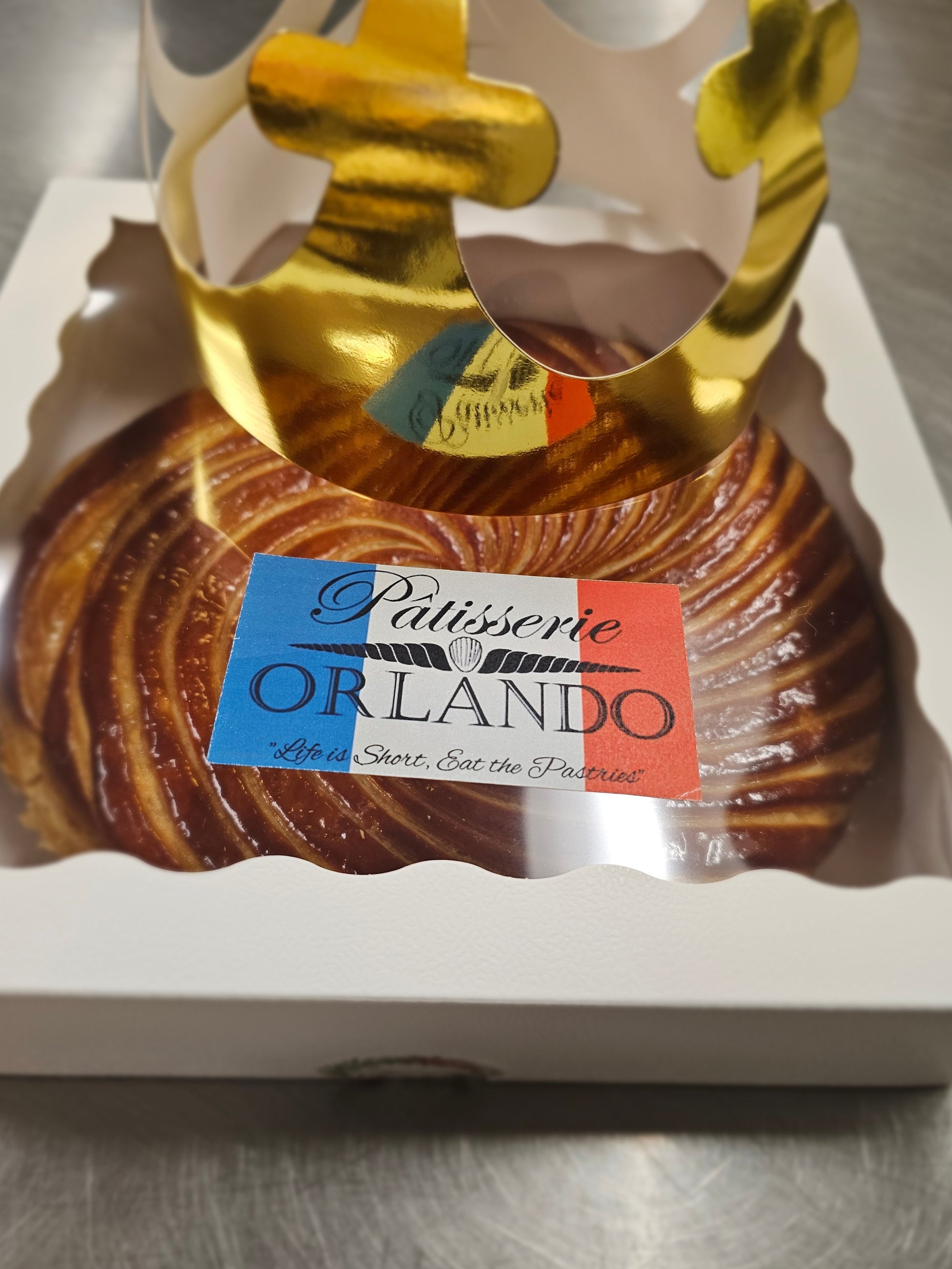 Galette des rois with a gold crown and 'Patisserie Orlando' label on a white box.
