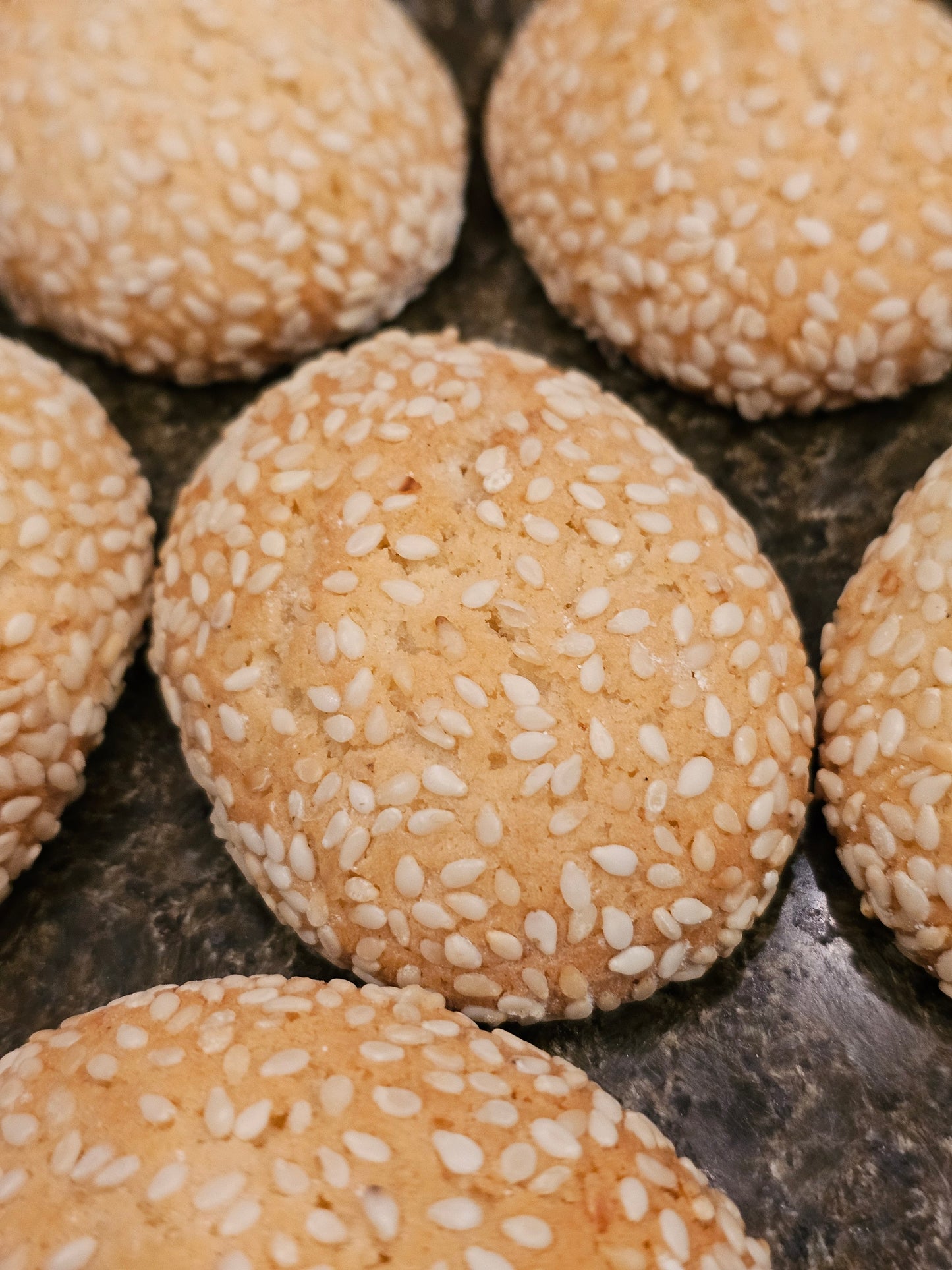 Close-up of sesame seed cookies on a stone surface.
