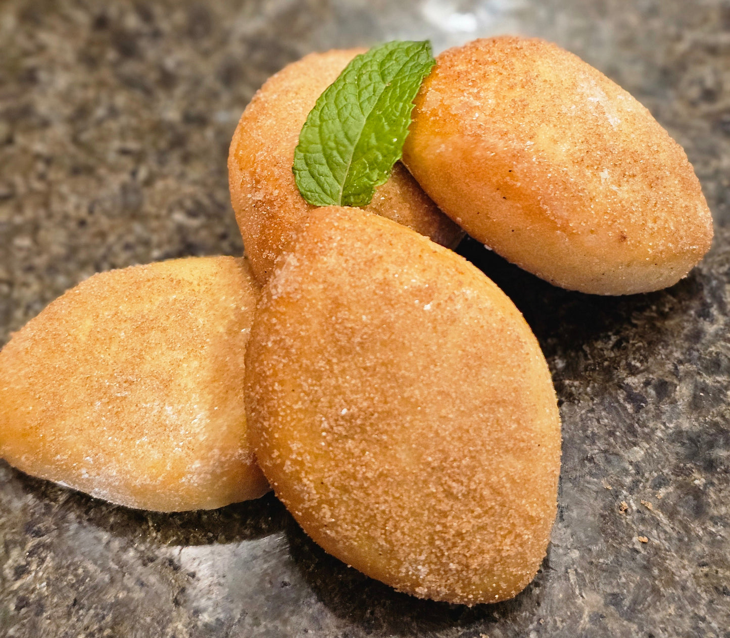 Lemon shaped cookies with a green leaf on a stone surface