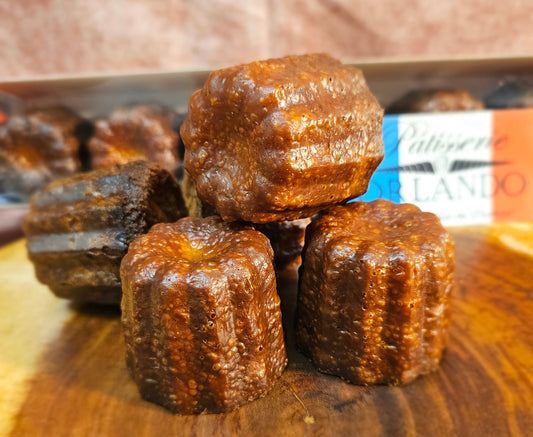 Canele stacked on a wooden board.