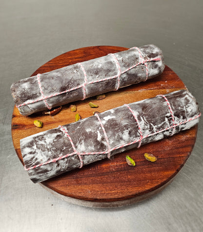 Two chocolate salamis on a wooden board with some nuts.