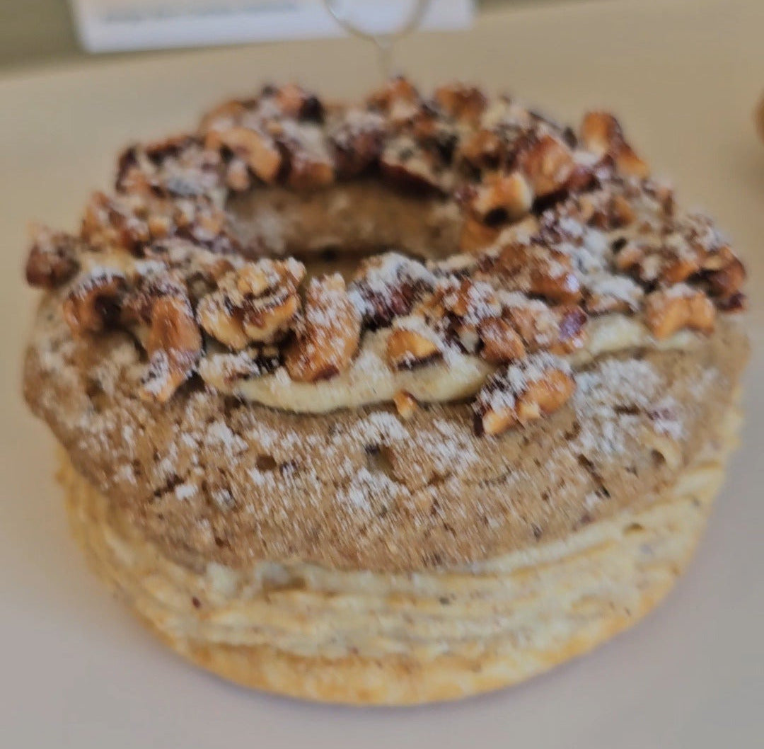 paris brest with powdered sugar and hazelnuts on a white surface
