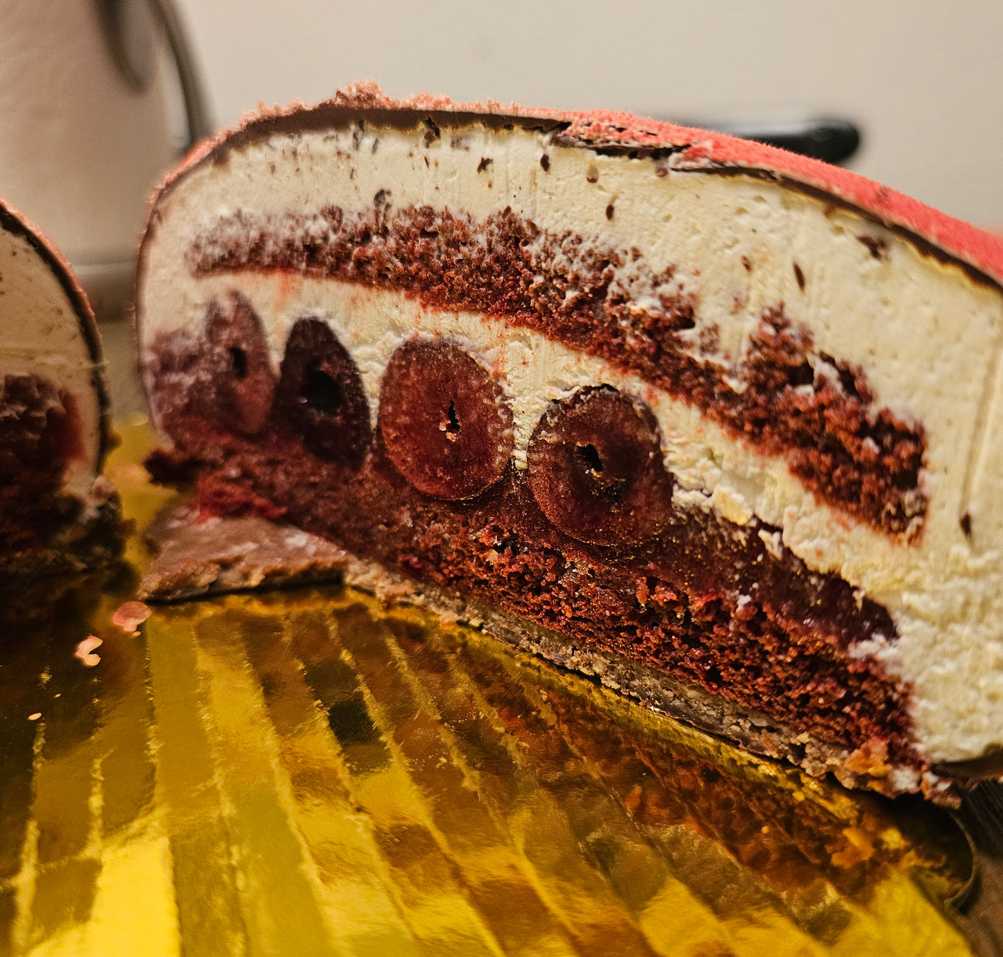Slice of cake showing layers of cake, cream and whole cherries.