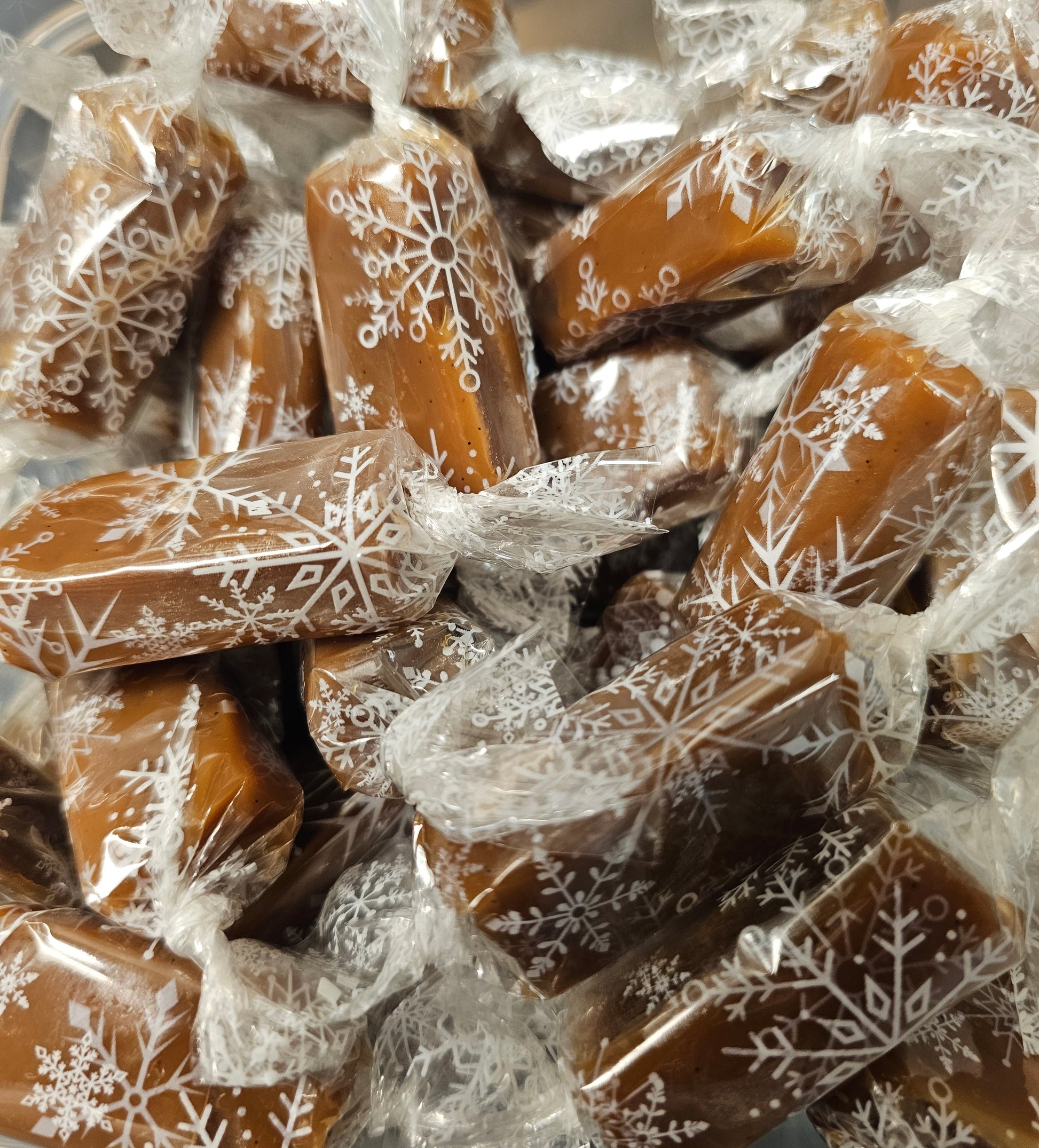 Caramels wrapped with white snowflake designs in clear wrappers.